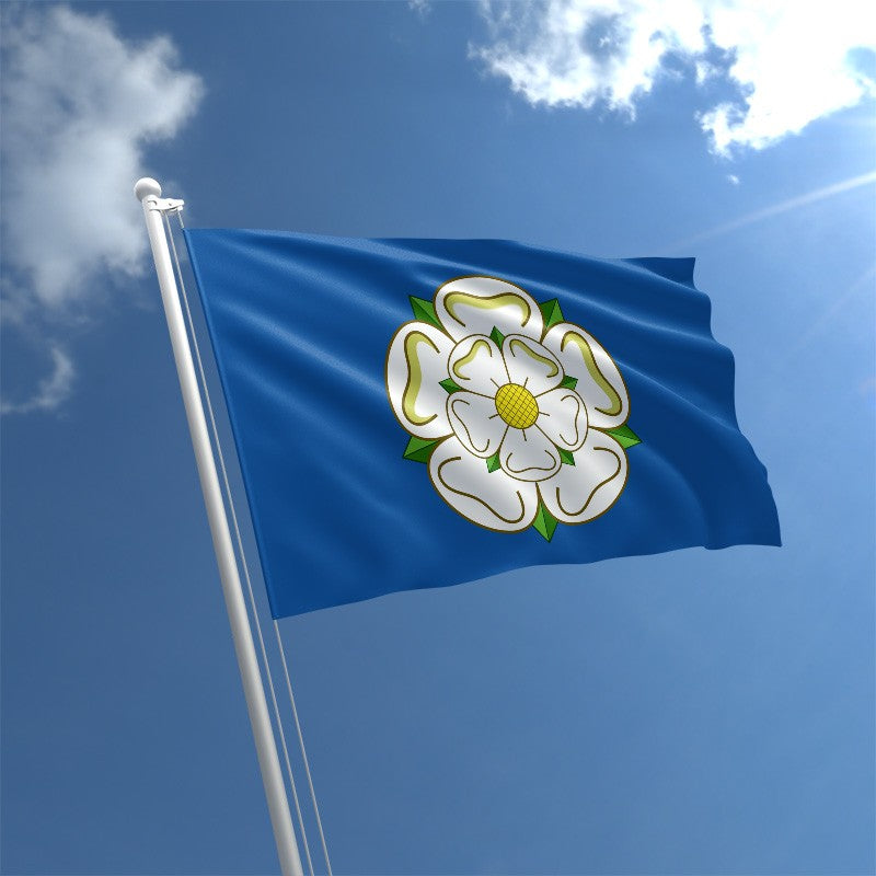 A photograph of the Yorkshire flag, a blue flag with a stylised white rose at the centre of it, waving against the backdrop of a blue sky.
